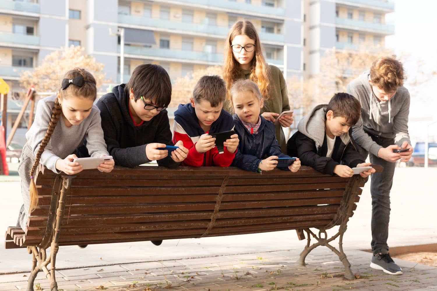 Grupa dzieci grająca na smartfonach poza domem