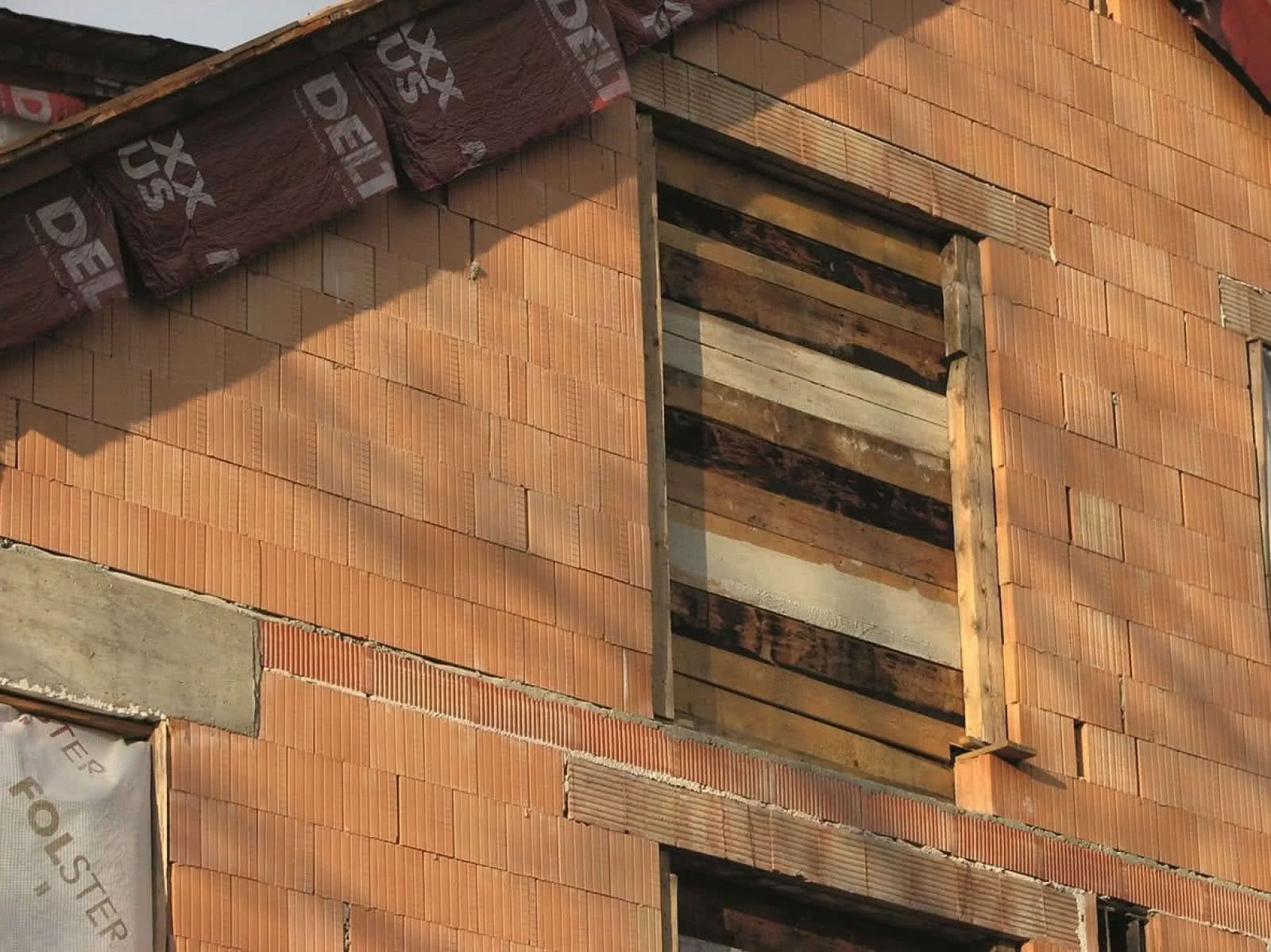 Zabezpieczenie otworów okiennych deskami przed nadejściem zimy budynku w stanie surowym. fot. Tomasz Rybarczyk